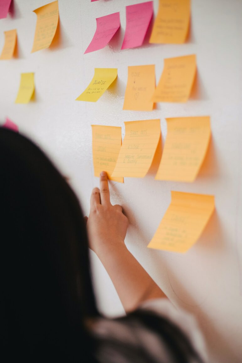 person gestures at post-it note on wall